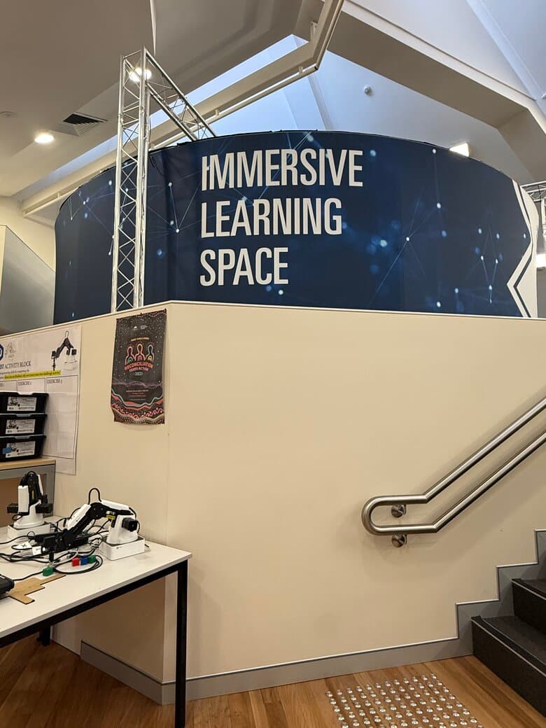 「IMMERSIVE LEARNING SPACE」のサインが掲げられたノックス・グラマー・スクールの学習施設iHubの内観。手前の机にはロボットアームが並ぶ
