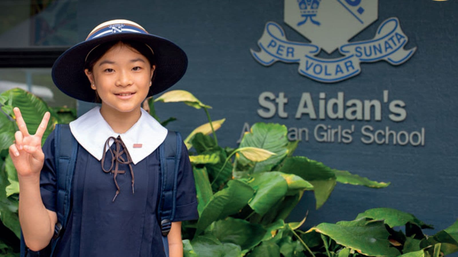 St Aidan’s Anglican Girls’ School の校門前で制帽をかぶって笑顔を見せる日本人の生徒