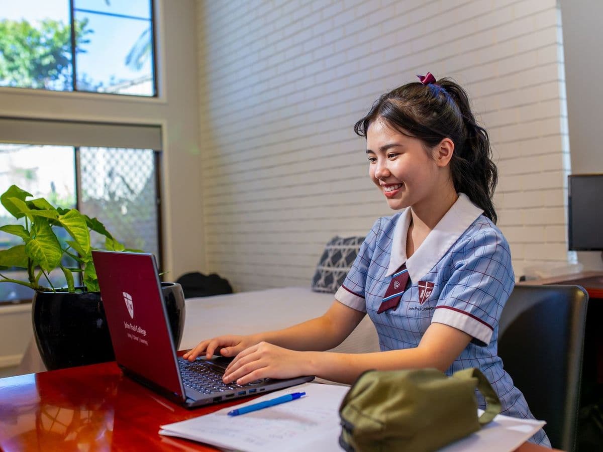寮の自室でノートパソコンに向かって学習するJohn Paul Collegeの留学生